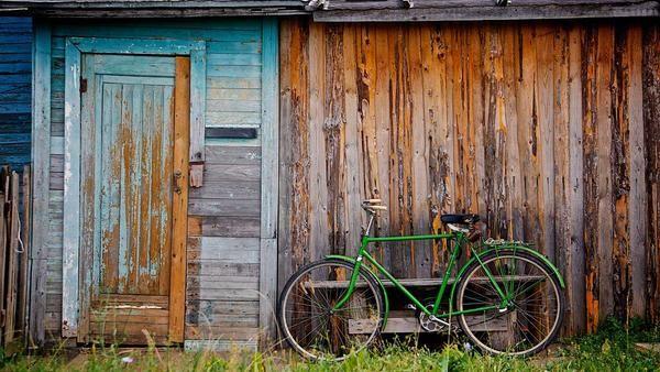Illustrative green bicycle beside a weathered wooden shed